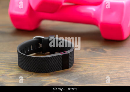 Appareil portable, wirst type watch Sports Tracker et de couleur rose dumb-bell sur une planche en bois Banque D'Images
