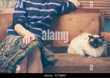 Une jeune femme est assise sur un canapé avec son chat Banque D'Images