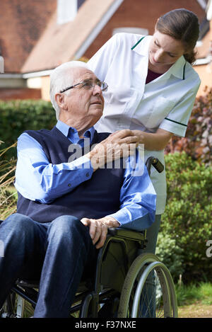 Carer poussant Senior Man In Wheelchair Banque D'Images