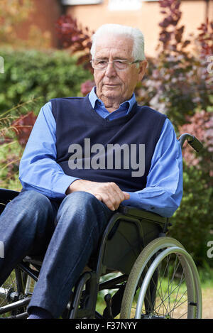 Déprimé Senior Man Sitting Outdoors In Wheelchair Banque D'Images