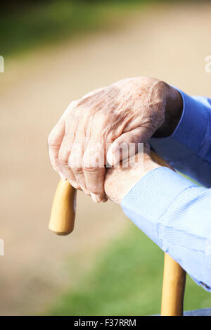 Close Up of Senior Man's mains reposant sur bâton de marche Banque D'Images