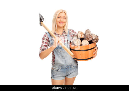 Jeune femme blonde en chemise à carreaux tenant un seau plein de billes et de transporter une hache à l'épaule Banque D'Images