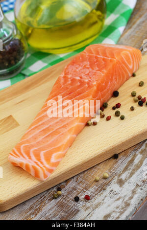 Pavé de saumon cru avec du poivre noir sur planche de bois Banque D'Images