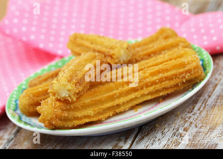 Des churros espagnol sur la plaque avec un chiffon rose en arrière-plan Banque D'Images