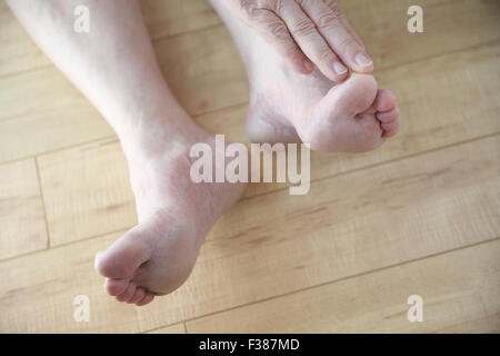 Un homme plus âgé lui touche les orteils d'une position assise sur le sol. Banque D'Images