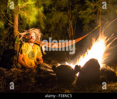 Feu de camp sur une plage rocheuse avec couple sitting Banque D'Images