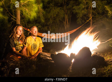 Feu de camp sur une plage rocheuse avec couple sitting Banque D'Images