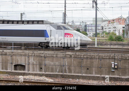 Gris et Bleu train à grande vitesse sur un arrière-plan flou et urbain Banque D'Images