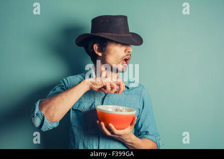 Un jeune cow-boy est à la surprise comme il est eating popcorn Banque D'Images