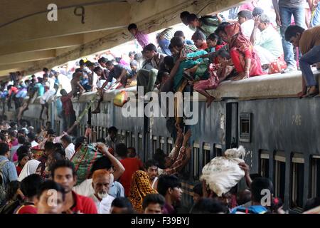 Les gens, y compris les enfants, descendre du toit d'un train entrant en gare de kamalapur à Dhaka le 1 octobre 2015.Comme il n'y avait pas de place à l'intérieur, ils ont voyagé sur le toit, risquent leur vie et leur intégrité physique pour revenir à la ville après les vacances de l'Aïd. Banque D'Images