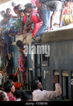 Les gens, y compris les enfants, descendre du toit d'un train entrant en gare de kamalapur à Dhaka le 1 octobre 2015.Comme il n'y avait pas de place à l'intérieur, ils ont voyagé sur le toit, risquent leur vie et leur intégrité physique pour revenir à la ville après les vacances de l'Aïd. Banque D'Images