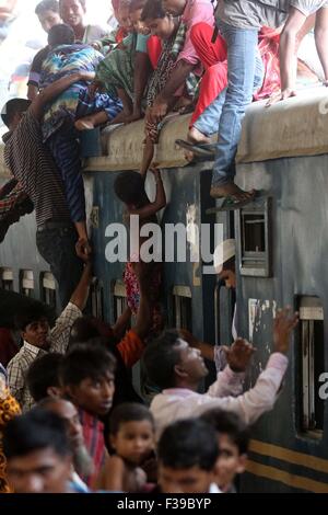 Les gens, y compris les enfants, descendre du toit d'un train entrant en gare de kamalapur à Dhaka le 1 octobre 2015.Comme il n'y avait pas de place à l'intérieur, ils ont voyagé sur le toit, risquent leur vie et leur intégrité physique pour revenir à la ville après les vacances de l'Aïd. Banque D'Images