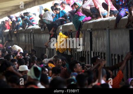 Les gens, y compris les enfants, descendre du toit d'un train entrant en gare de kamalapur à Dhaka le 1 octobre 2015.Comme il n'y avait pas de place à l'intérieur, ils ont voyagé sur le toit, risquent leur vie et leur intégrité physique pour revenir à la ville après les vacances de l'Aïd. Banque D'Images