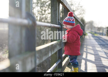 Garçon debout sur un pont en regardant river Banque D'Images