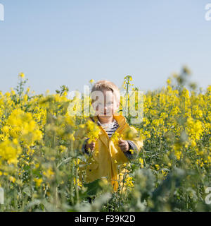 Portrait d'un garçon debout dans le champ de fleurs jaunes Banque D'Images