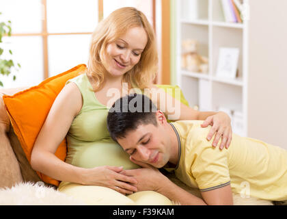 Mari est à l'écoute du rythme cardiaque de bébé couché sur le ventre de sa femme enceinte Banque D'Images