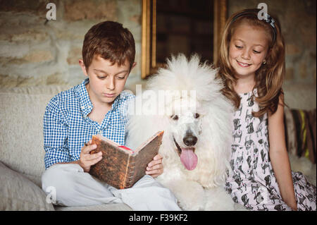 Garçon et fille lire un livre avec leur animal de compagnie chien caniche Banque D'Images