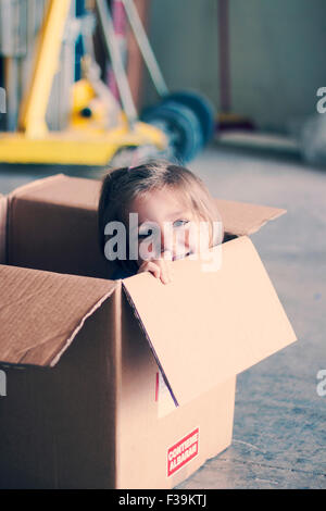 Smiling Girl sitting à l'intérieur d'une boîte en carton Banque D'Images