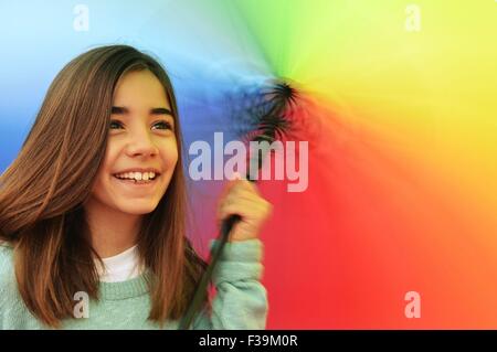 Portrait of a smiling girl twirling un parapluie multi-couleur Banque D'Images