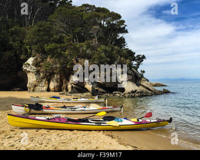 Trois kayaks de mer sur la plage au arrosage Cove, parc national Abel Tasman, Nouvelle-Zélande Banque D'Images