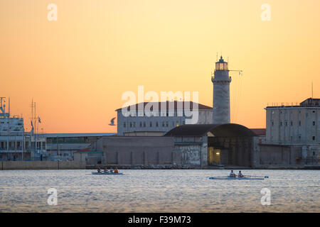 Italie Trieste Harbour, juste après le coucher du soleil sur la pratique des rameurs les eaux calmes de la mer Adriatique dans le port de Trieste. Banque D'Images