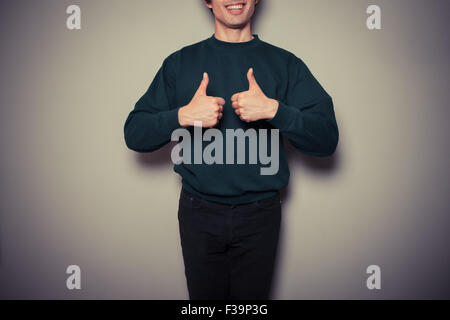 Un jeune homme est giving Thumbs up dans l'approbation Banque D'Images