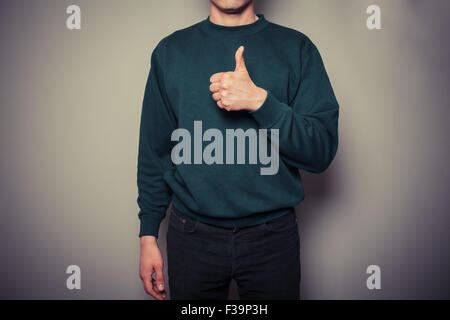 Un jeune homme est giving Thumbs up dans l'approbation Banque D'Images