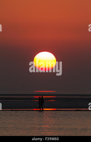West Kirby, Wirral, Merseyside, Royaume-Uni. 2 octobre, 2015. un couple en train de marcher sur le mur ouest du lac marin, Kirby, Wirral, Merseyside, passent devant le soleil couchant - Vendredi 2 Octobre 2014 Crédit : Damian Waters/Alamy Live News Banque D'Images