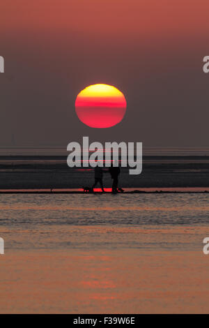 West Kirby, Wirral, Merseyside, Royaume-Uni. 2 octobre, 2015. Un couple en train de marcher sur le mur ouest du lac marin, Kirby, Wirral, Merseyside, passent devant le soleil couchant - Vendredi 2 Octobre 2014 Crédit : Damian Waters/Alamy Live News Banque D'Images