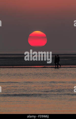 West Kirby, Wirral, Merseyside, Royaume-Uni. 2 octobre, 2015. Un couple en train de marcher sur le mur ouest du lac marin, Kirby, Wirral, Merseyside, passent devant le soleil couchant - Vendredi 2 Octobre 2014 Crédit : Damian Waters/Alamy Live News Banque D'Images