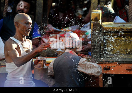 Katmandou, Népal. 09Th Oct, 2015. Un prêtre local offrant de l'eau sainte vers dévots pendant le char tirant festival de Rato Dans Macchendranath Lagankhel. © Narayan Maharjan/Pacific Press/Alamy Live News Banque D'Images