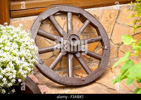 Roue de chariot en bois s'appuie contre le mur Banque D'Images