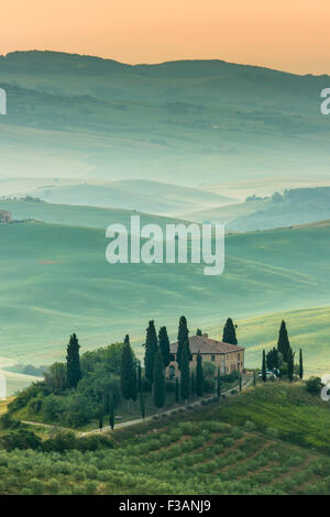 La toscane, ferme isolée dans le pays d'or et verts collines du Val d'Orcia, tôt le matin. Paysage italien. Banque D'Images