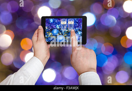 L'homme prend photo de Noël encore la vie - deux verres de champagne dans les boules et de guirlandes de Noël bleu sur violet blured Christmas Tree Banque D'Images