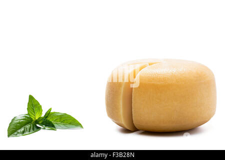 Fromage rond jaune et les feuilles de basilic sur fond blanc Banque D'Images