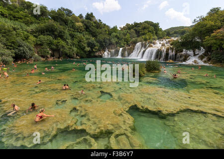 Les gens de la baignade à un lac en face de chutes d'eau à le Parc National de Krka en Croatie en Croatie. Banque D'Images