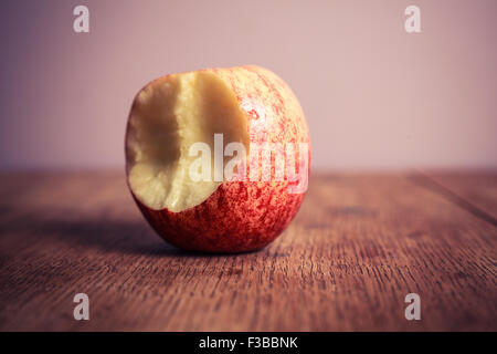 Un apple à moitié mangé sur une table en bois Banque D'Images