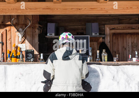 Vue arrière du casque de ski femme avec l'attente à Mountain lodge compteur pour un verre Banque D'Images