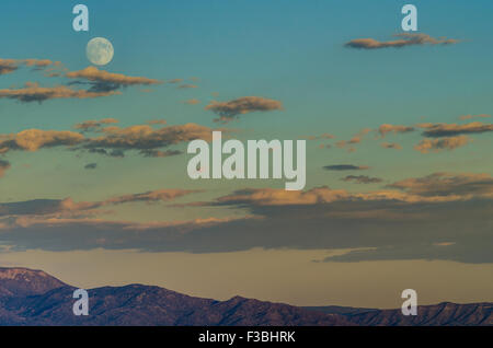 Pleine lune se lever sur les montagnes de Sandia et Albuquerque, Nouveau Mexique, USA. Banque D'Images