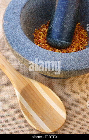 Piment rouge séché épicé dans un mortier avec du granit de cuillère de cuisson sur un tissu jute Banque D'Images