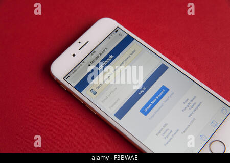Or et blanc Apple iPhone 6 avec Facebook Connectez-vous sur l'écran sur un fond rouge Banque D'Images
