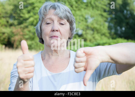 Femme de la vieillesse showing Thumbs up et down Banque D'Images