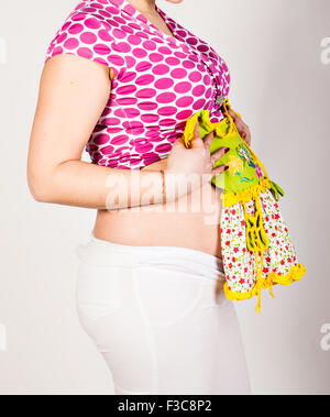 Pregnant woman holding baby clothing Banque D'Images