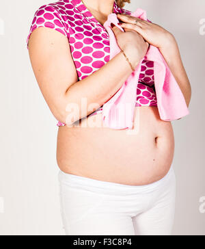 Pregnant woman holding baby clothing Banque D'Images