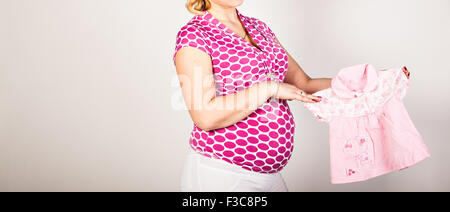 Pregnant woman holding baby clothing Banque D'Images