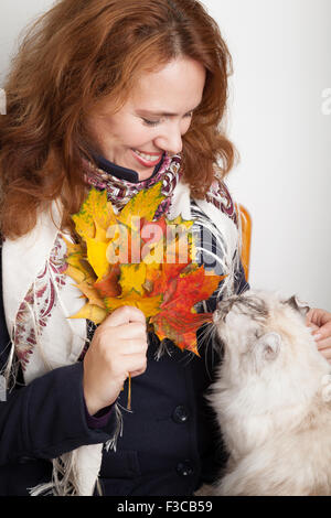 Portrait of Young Caucasian woman in traditional Russian cou foulard avec chat blanc et coloré de l'automne feuilles d'érable Banque D'Images