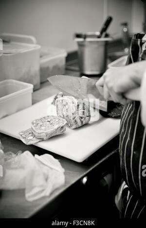 Chef slicing saucisse de porc Banque D'Images