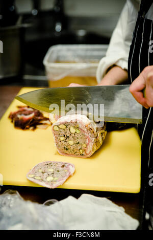 Chef slicing saucisse de porc Banque D'Images