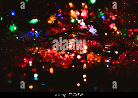 Des guirlandes de couleur lumineux ampoule brille dans le fond sombre, selective focus Banque D'Images