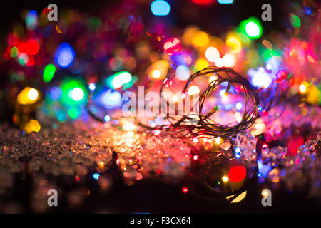 Des guirlandes de couleur lumineux ampoule brille dans le fond sombre, selective focus Banque D'Images